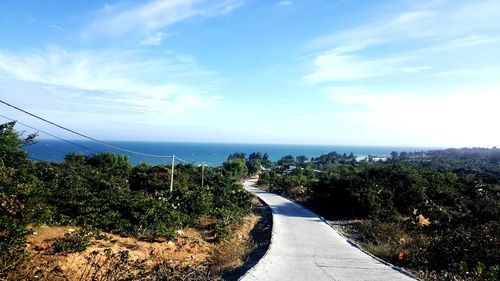 Road by sea against blue sky