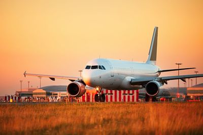 Airplane on field against sky during sunset