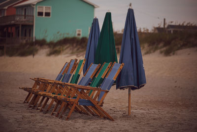 Empty chairs on beach against sky