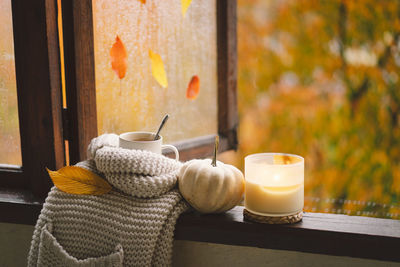 Still life details in home on a wooden window. sweater, candle, hot tea and autumn decor