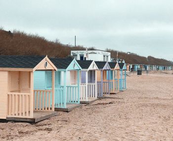 Beach huts in row against sky