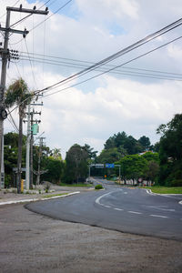 Road by electricity pylon against sky