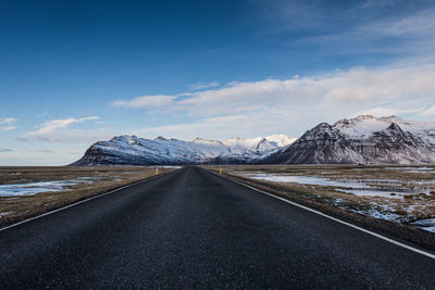 Road amidst snowcapped mountains against sky