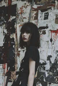Portrait of young woman standing against wall