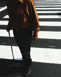 Low section of senior man with walking cane on road