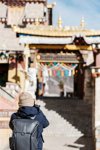 Rear view of woman with backpack standing at temple
