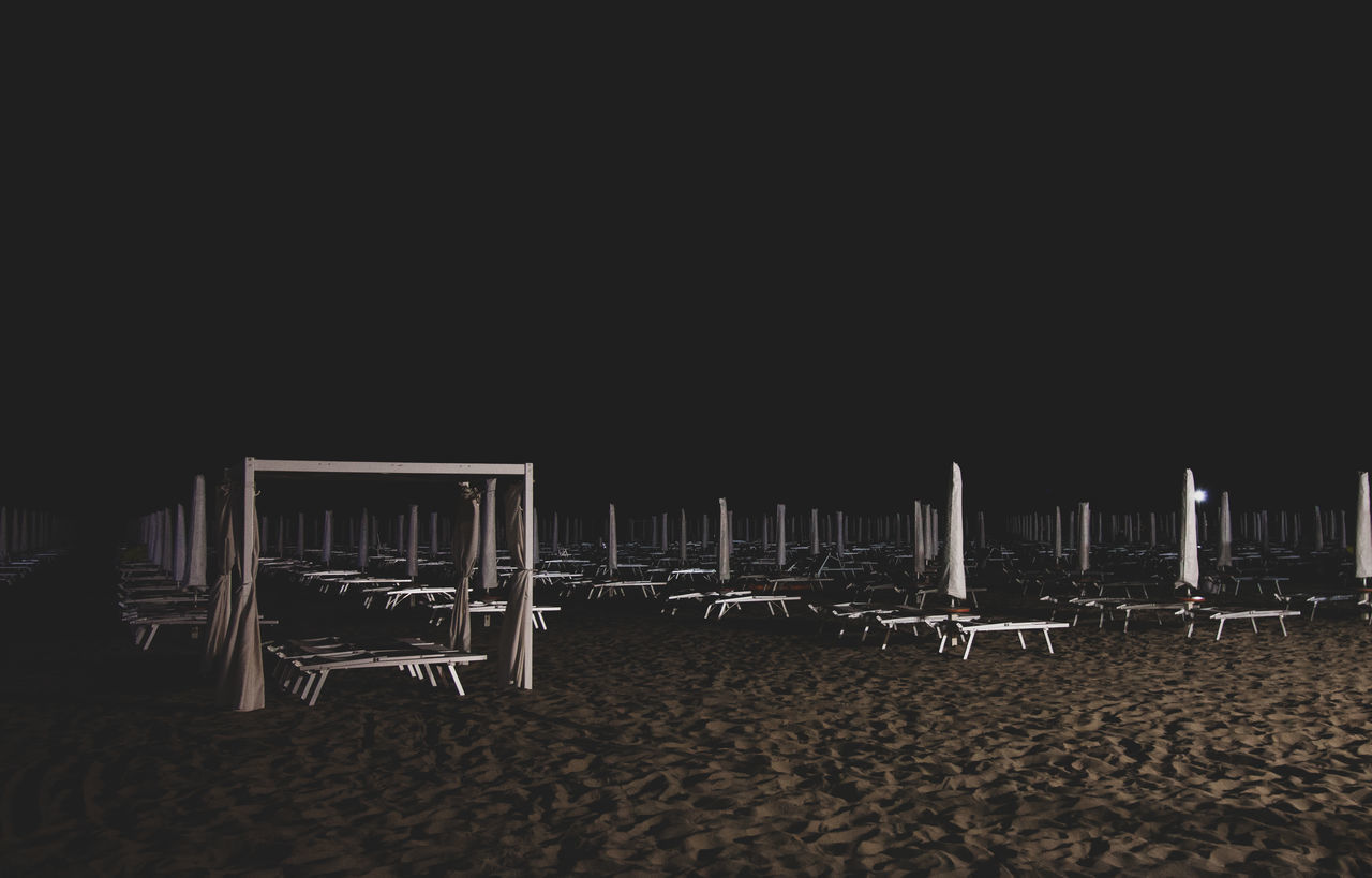 EMPTY CHAIRS ON BEACH AGAINST CLEAR SKY