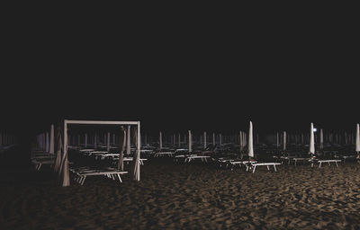 Empty chairs on beach against clear sky at night