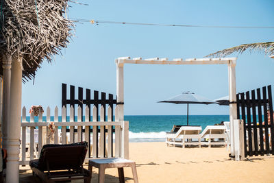 Chairs at beach against clear blue sky