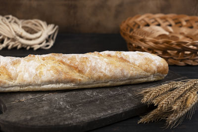 Homemade fresh crispy baguette bread in a cutting board. wooden background. side view.