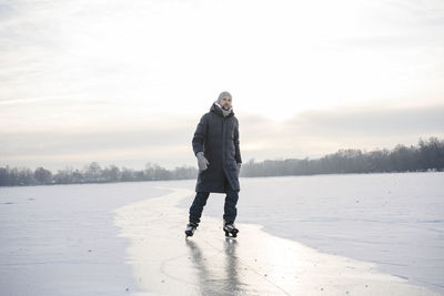 Man ice skating on frozen lake in winter