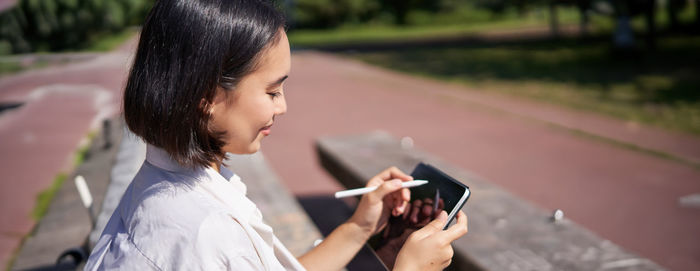 Side view of young woman using mobile phone