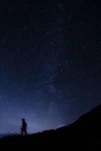 Low angle view of man standing against sky at night