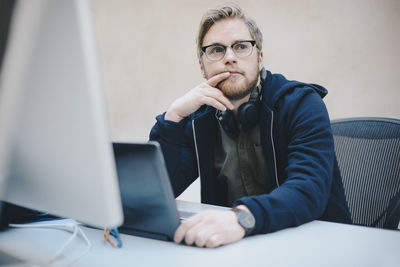 Thoughtful computer programmer sitting at desk in office