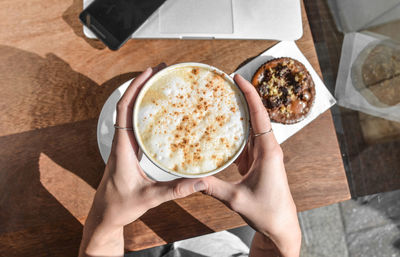 High angle view of hand holding coffee on table