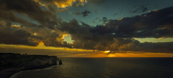 Scenic view of sea against dramatic sky during sunset