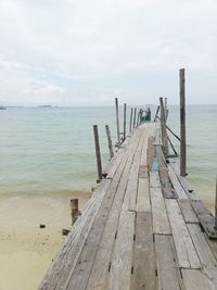 Wooden pier on beach against sky