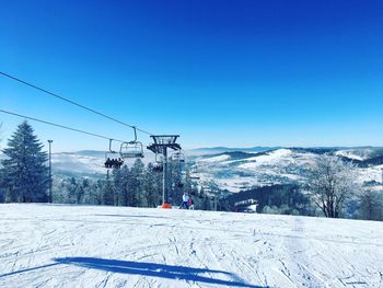 Snow covered landscape against clear blue sky