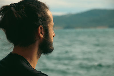 Side view of man looking at sea against sky