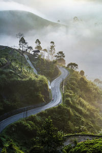 High angle view of winding road and  foggy valley against ray of sun light in the morning