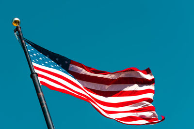 Low angle view of flag against clear blue sky