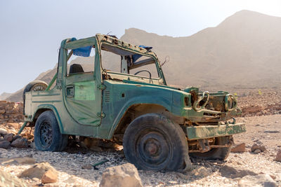 Old truck on road by mountain against clear sky