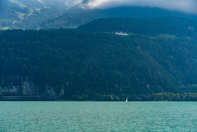 Scenic view of sea by mountain against sky
