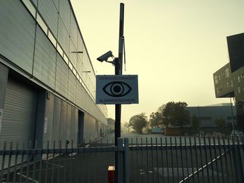 Road sign by building against sky