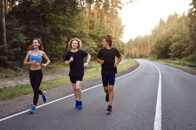 Full length of young woman running on road