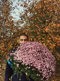 Low angle view of flowering plants against trees during autumn