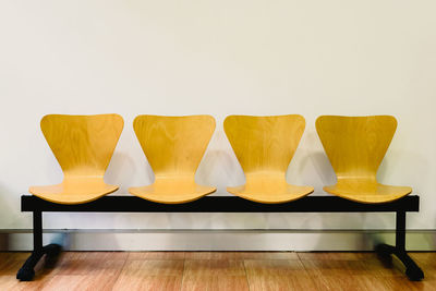 Empty chairs and tables on hardwood floor against wall