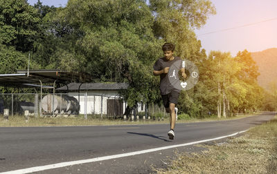 Full length of young man on road against trees