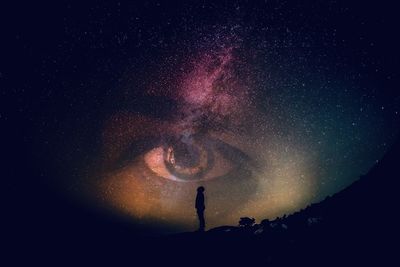 Low angle view of silhouette woman against star field at night