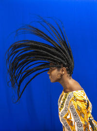 Young beautiful woman making motion with her hair. isolated blue background.