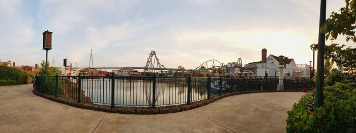 Bridge over river amidst buildings against sky during sunset