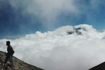 Rear view of man standing on mountain against sky