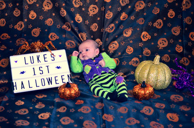 Cute baby relaxing by text on bed during halloween