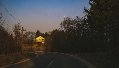 Empty road amidst trees against sky