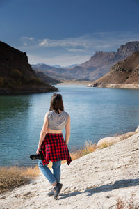 Rear view of woman standing on mountain against sky