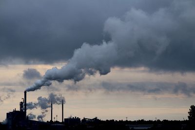 Smoke emitting from chimney against sky