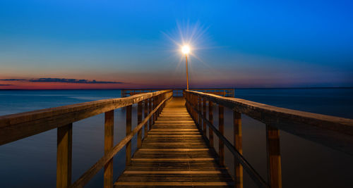 Pier over sea against sky during sunset