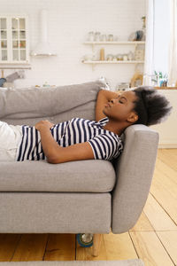 Side view of woman relaxing on sofa at home