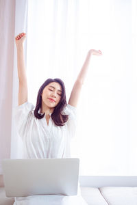 Young asian woman stretching her arms after using laptop.