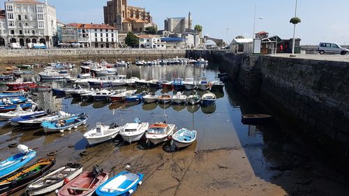 Sailboats moored on harbor by buildings in city