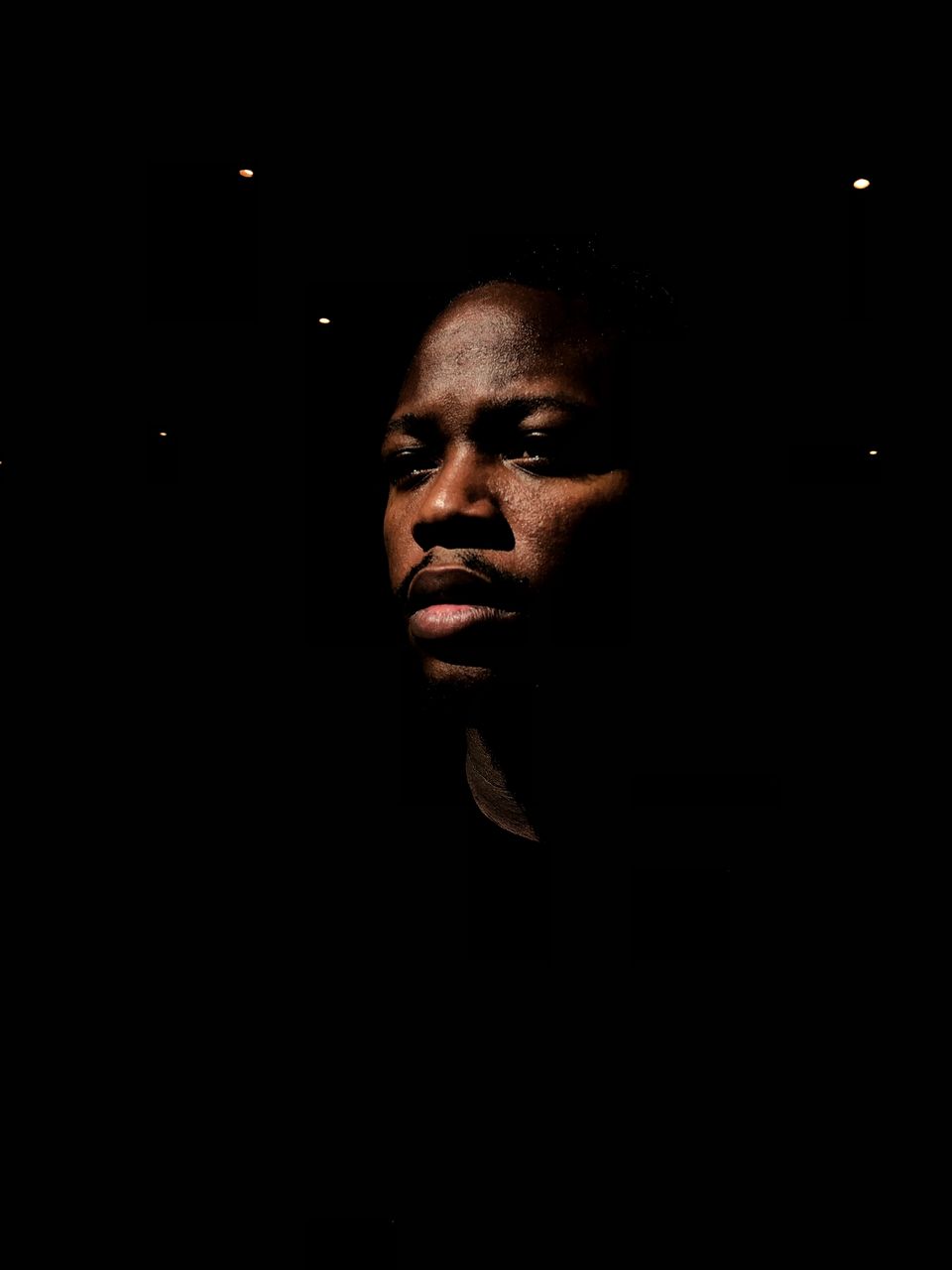 one person, dark, headshot, indoors, portrait, front view, copy space, young adult, lifestyles, real people, darkroom, looking, looking away, young men, black background, close-up, leisure activity, domestic room, contemplation, human face