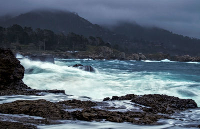 Scenic view of sea by mountains against sky