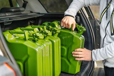 Person arranging oil canister in car trunk