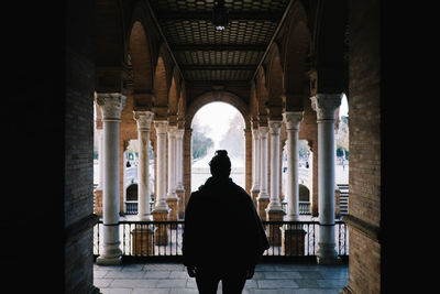 Rear view of woman standing in corridor of historic building