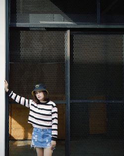 Portrait of woman standing against fence