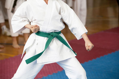 Midsection of man practicing karate on carpet